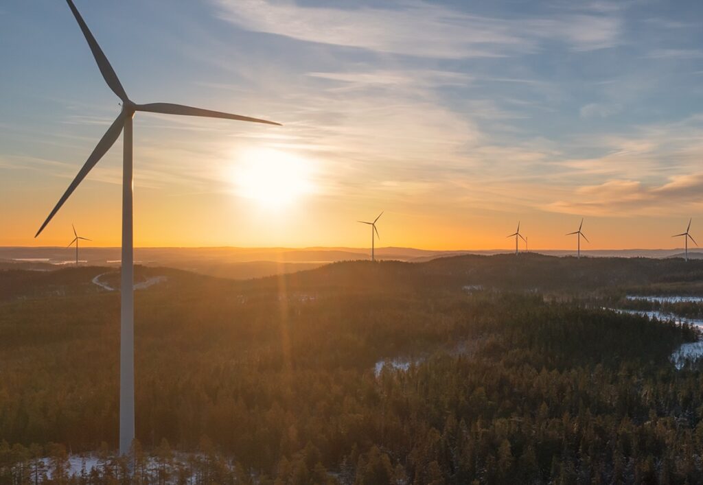 Vindkraftverk i solnedgång över skogslandskap
